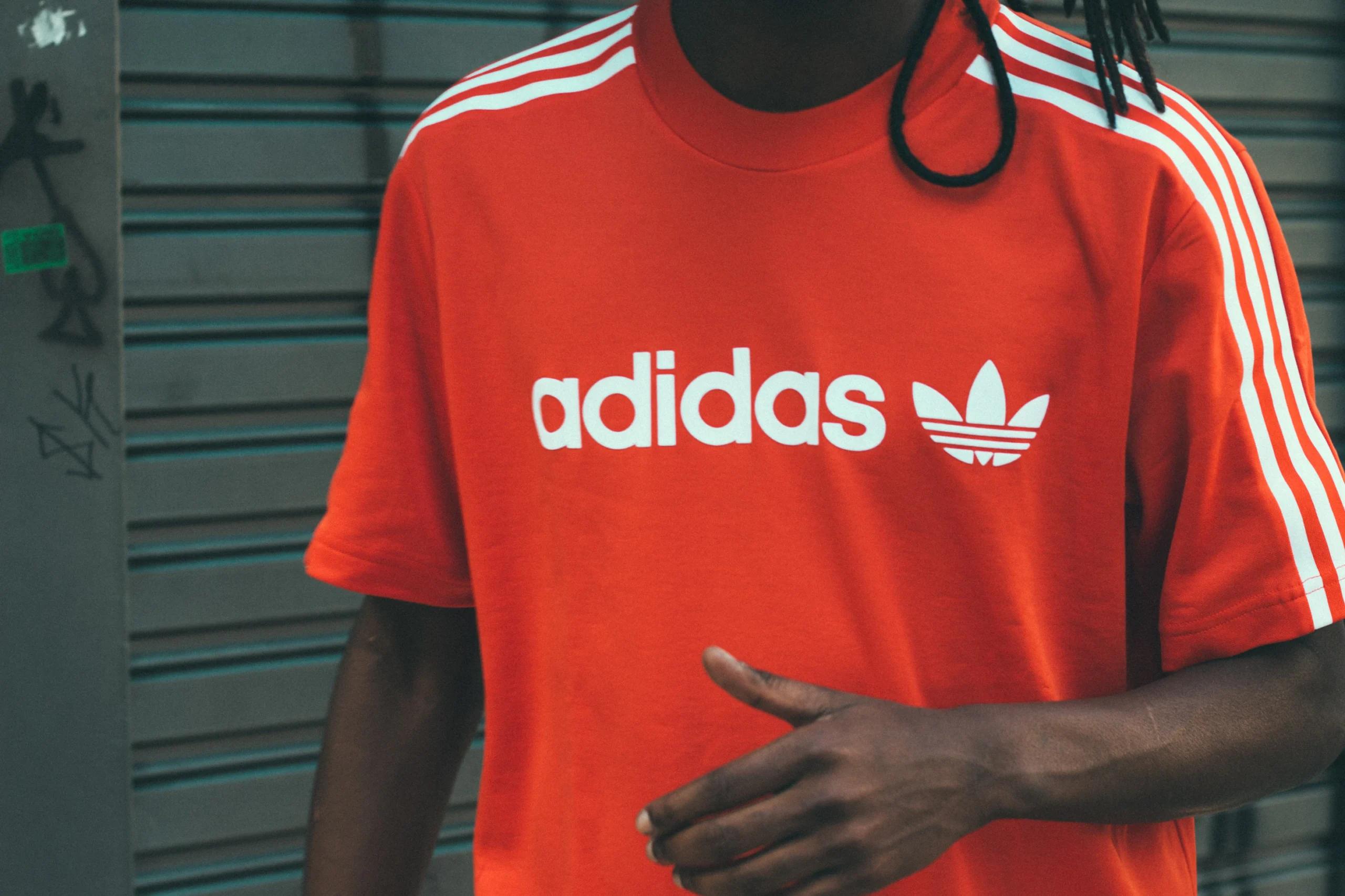 A man wearing a red and white Adidas T-shirt