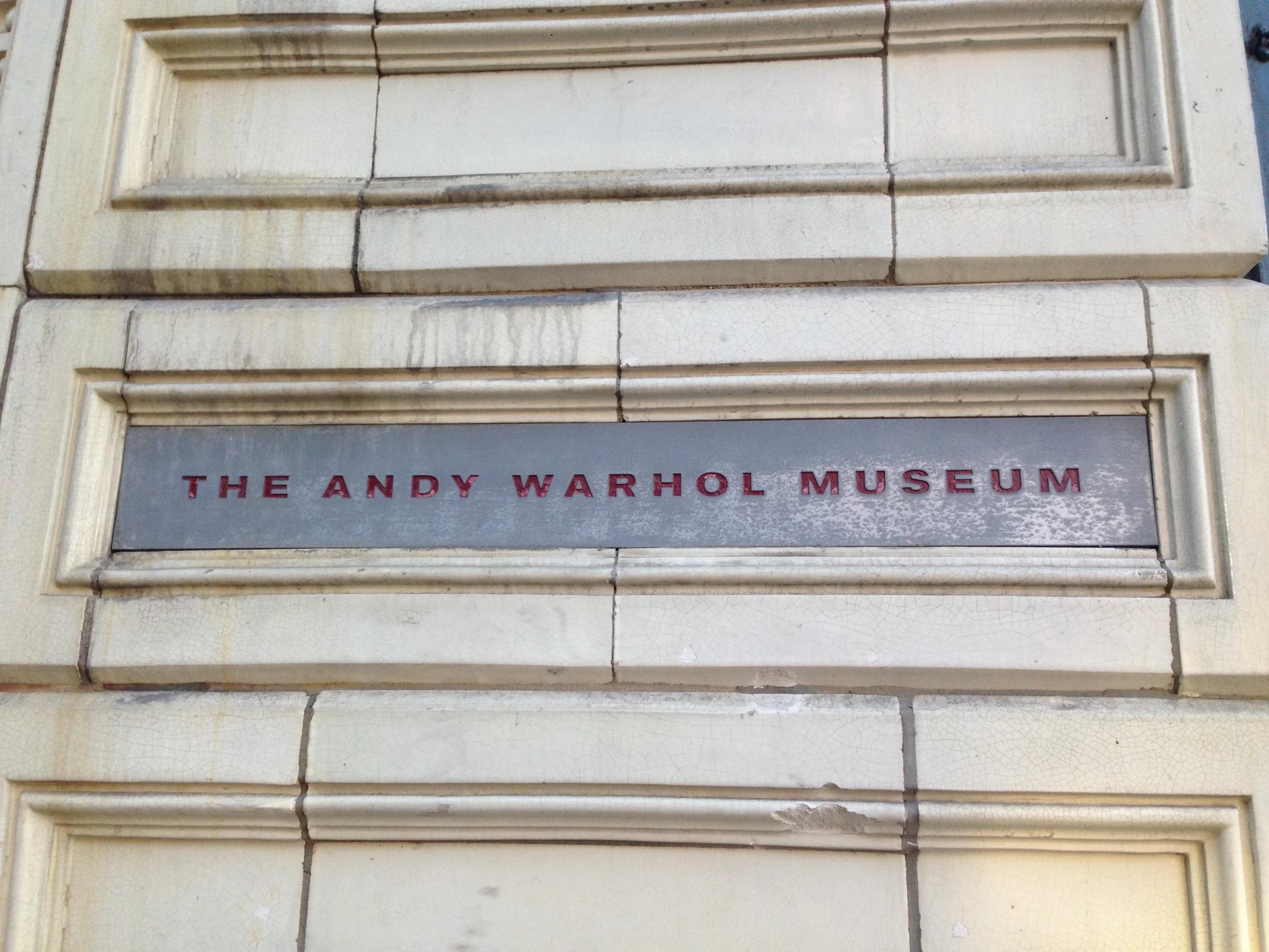 A sign on the side of a building that reads "The Andy Warhol Museum"