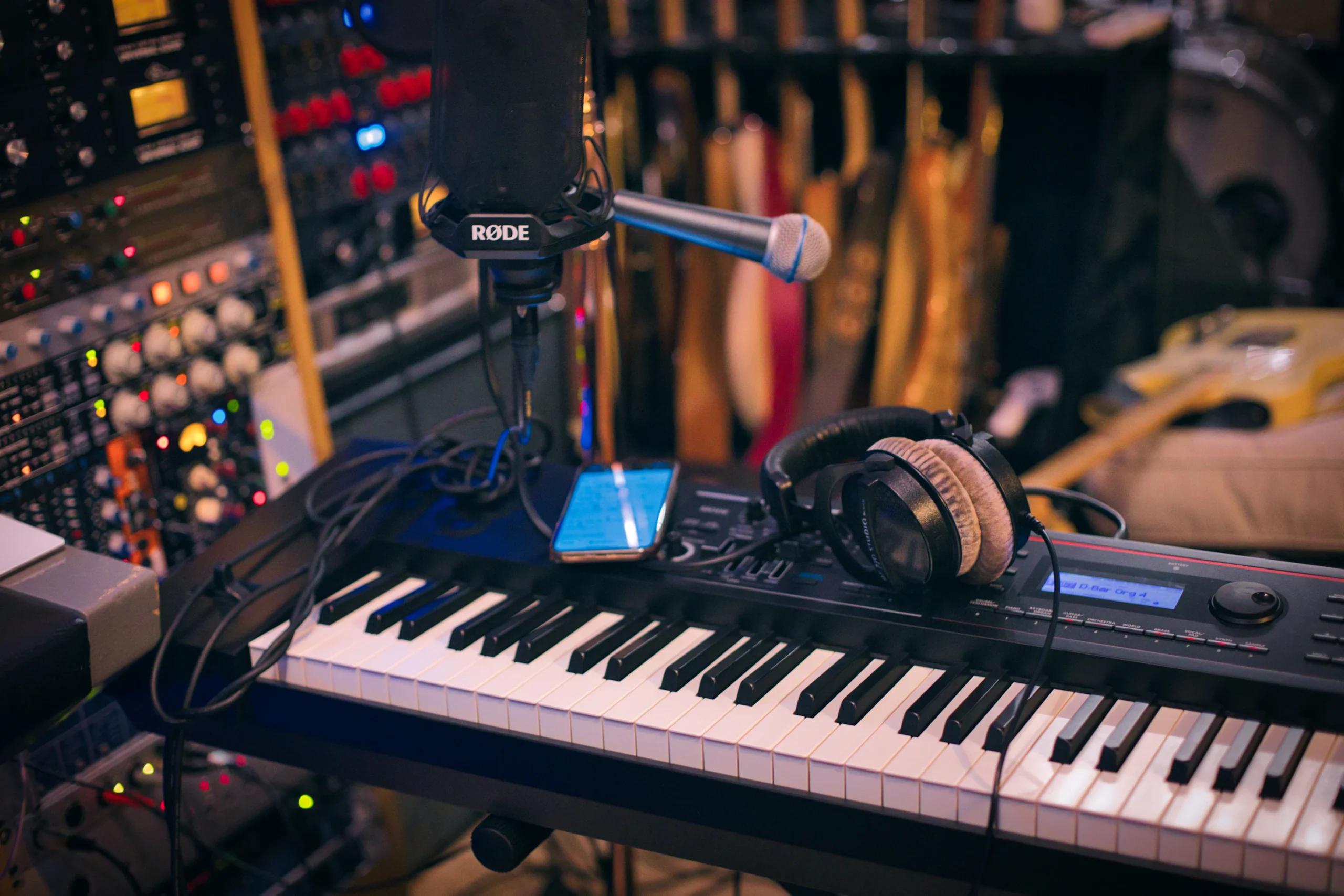 Synthesizer keyboard and a microphone, background of a recording room