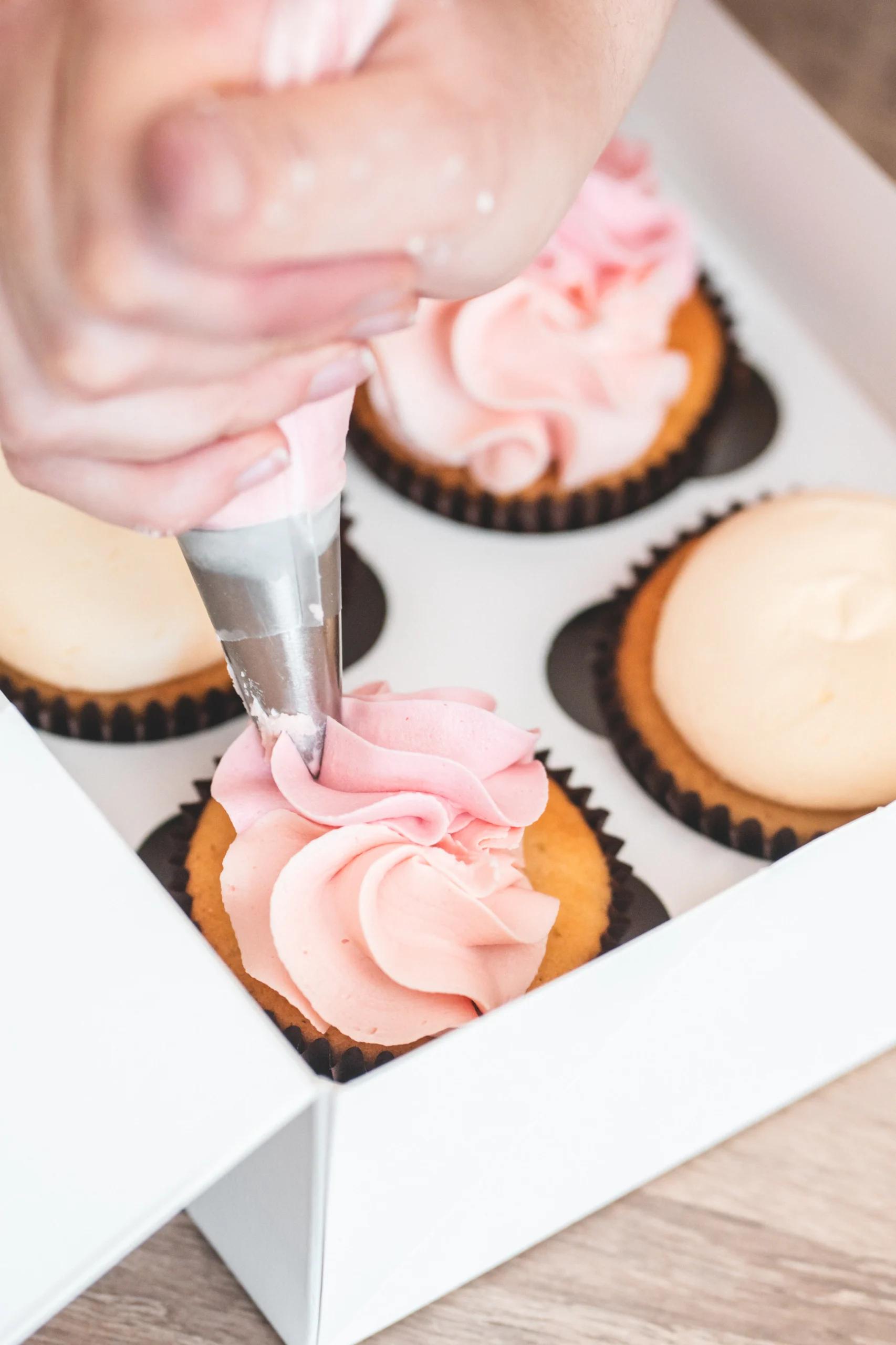 A pastry chef icing a cupcake